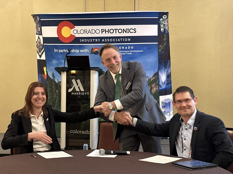 MOU signing ceremony between CPIA and MPQA at the Colorado Photonics Industry Association banner
